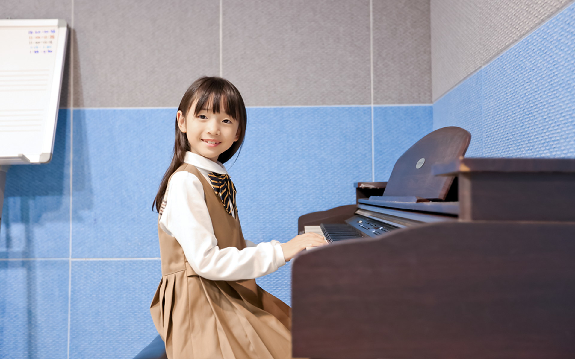 피아노 앞에 앉아 건반을 누르는 여자아이