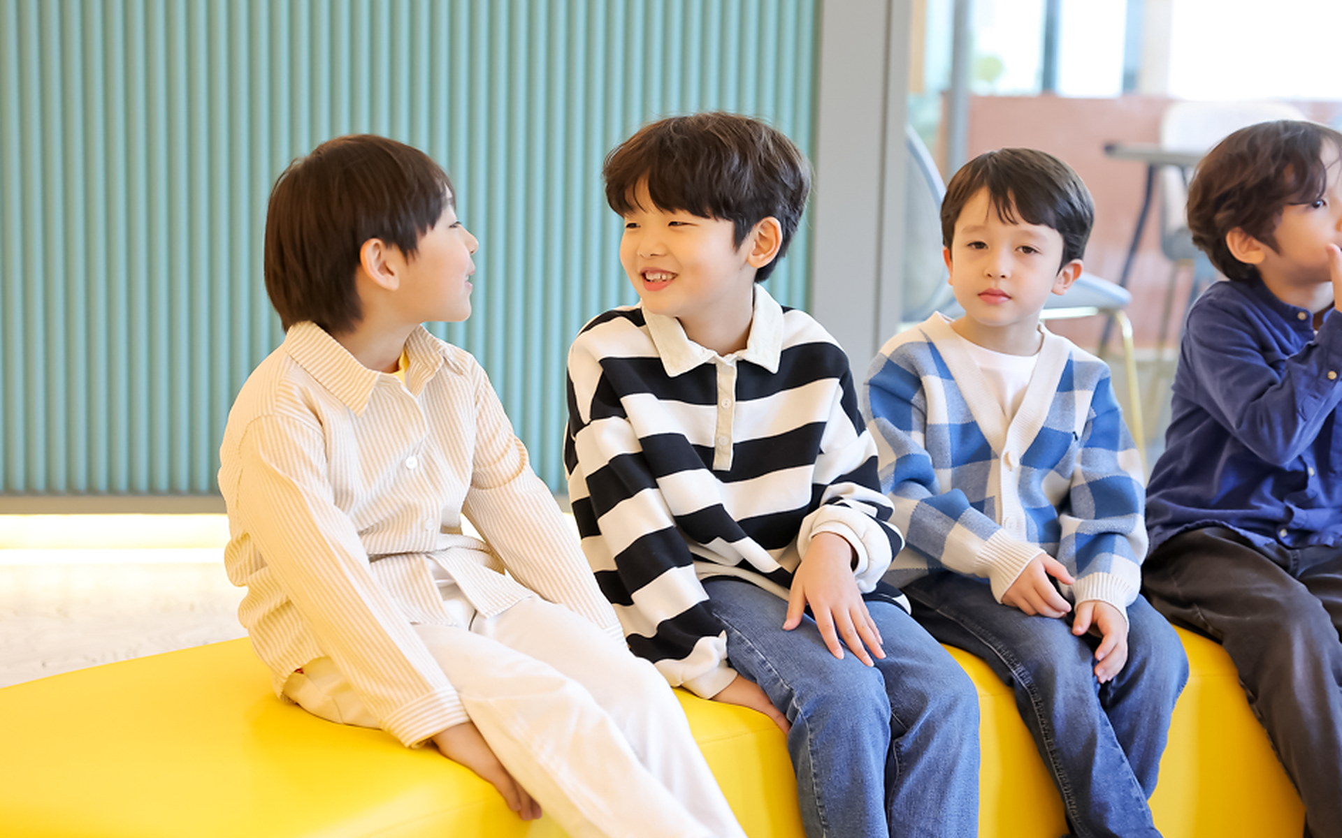 노란 소파에 나란히 앉아 웃는 아이들